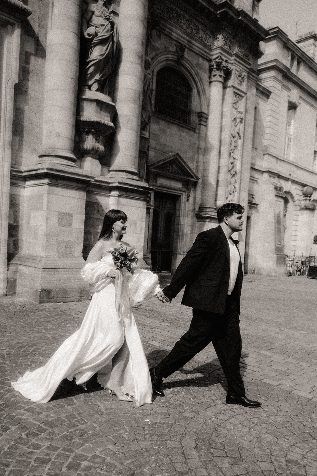 Un couple de mariés marchant dans la ville. La robe de la mariée vol au vent.