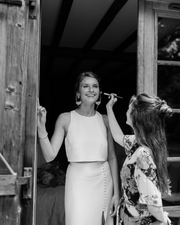 Photo en noir et blanc de Julia Marty la maquilleuse entrain de maquiller une mariée. Toutes les deux souries.